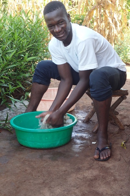Young man washing his hands smiling at the camera