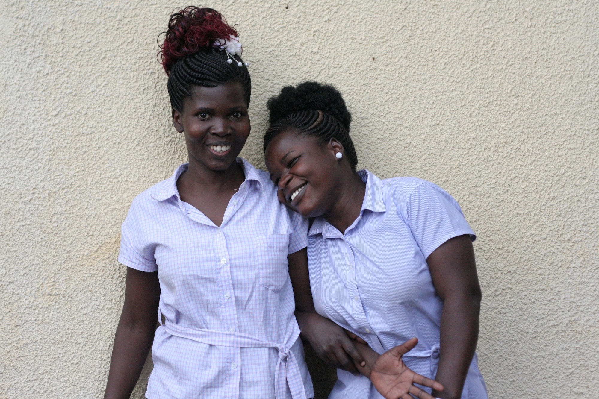Two women standing in front of a wall smiling