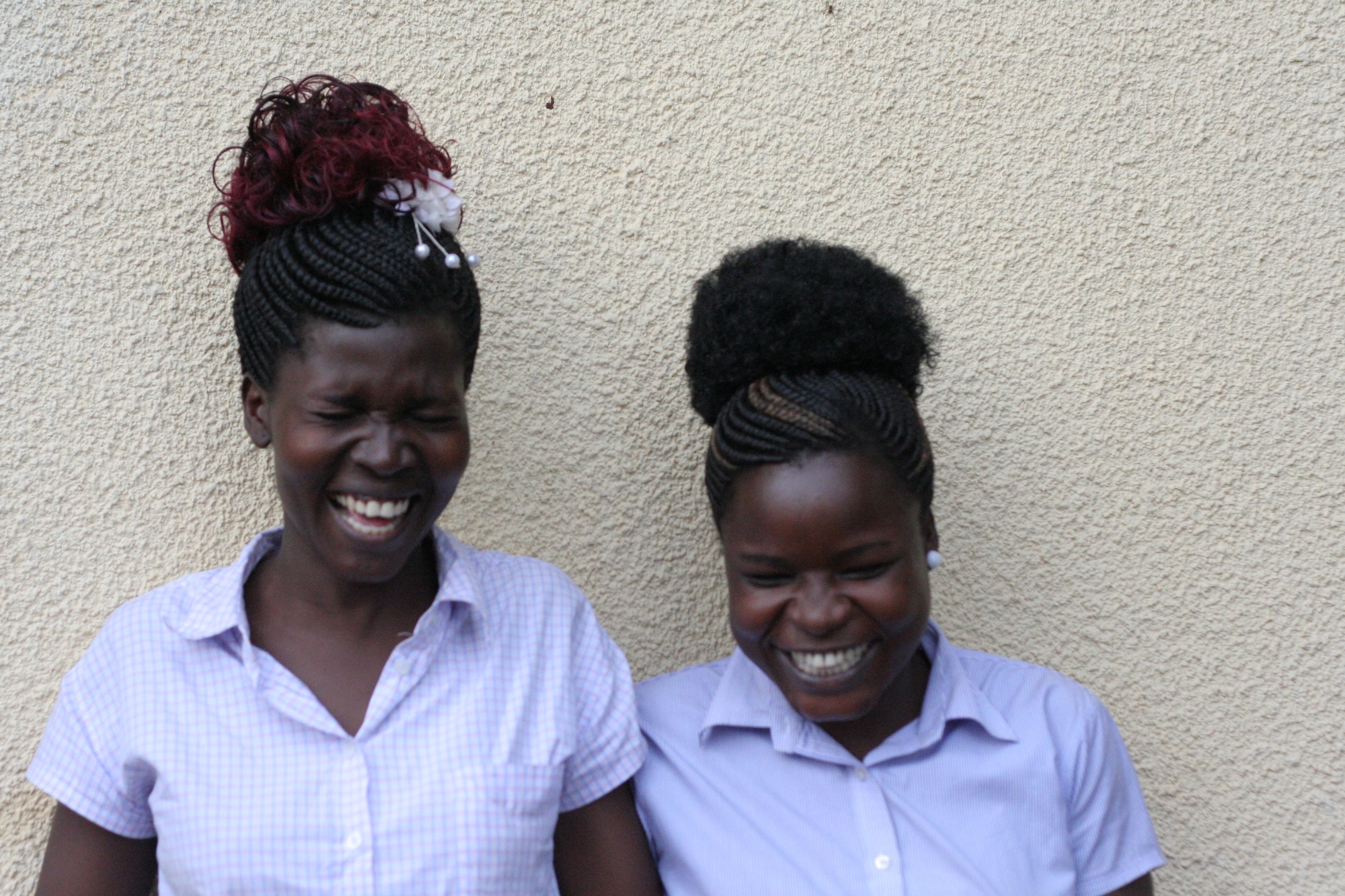 Two women standing in front of a wall laughing