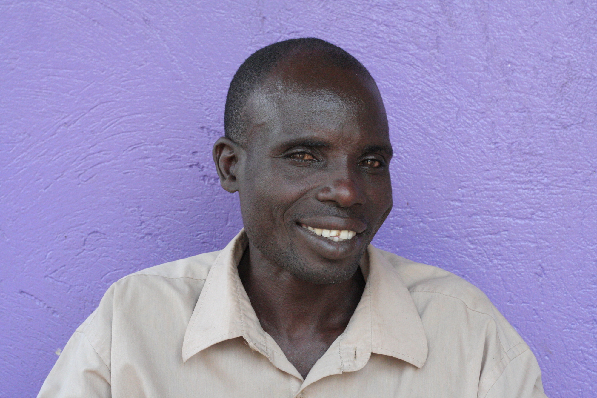 Man smiling in front of a purple wall