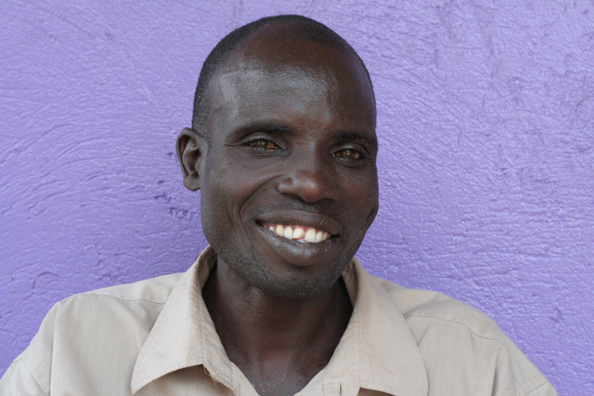 Man smiling in front of a purple wall