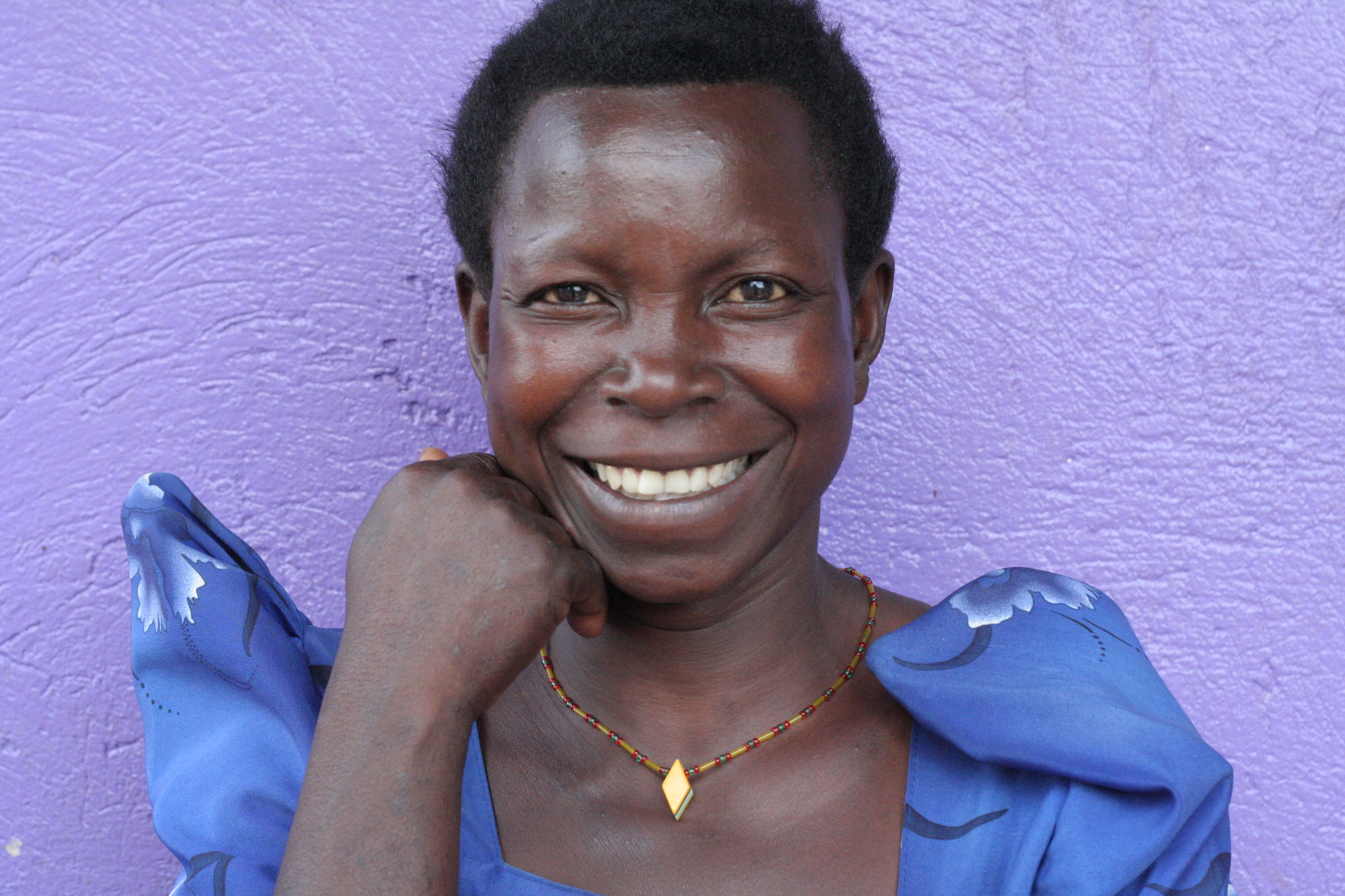 Woman smiling in front of a purple wall