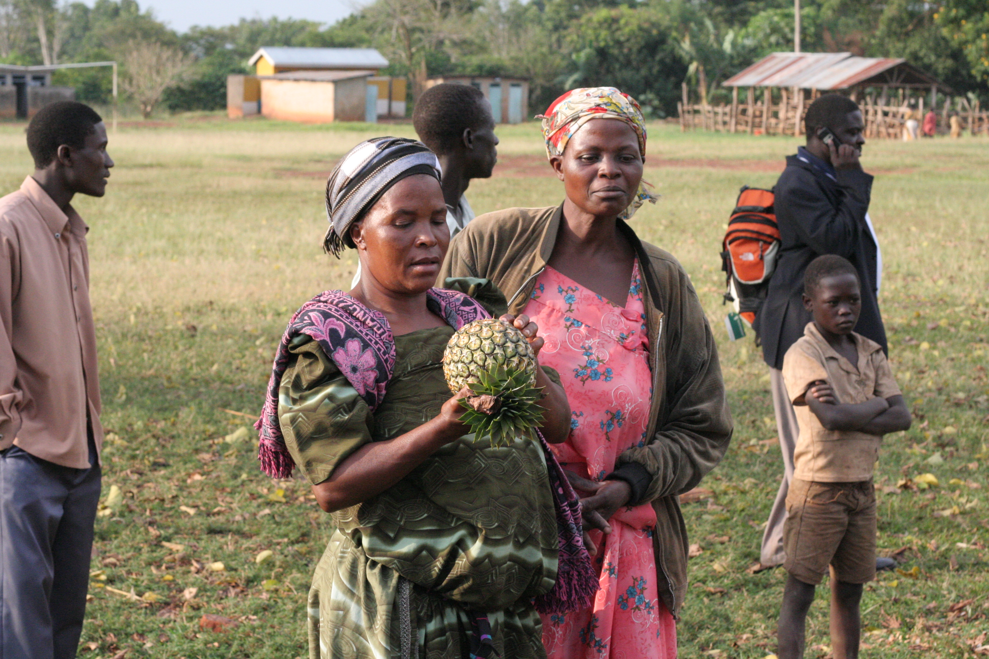 People standing in a field, one with a pineapple