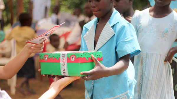 Volunteer with ROWAN A woman giving a gift to a young girl