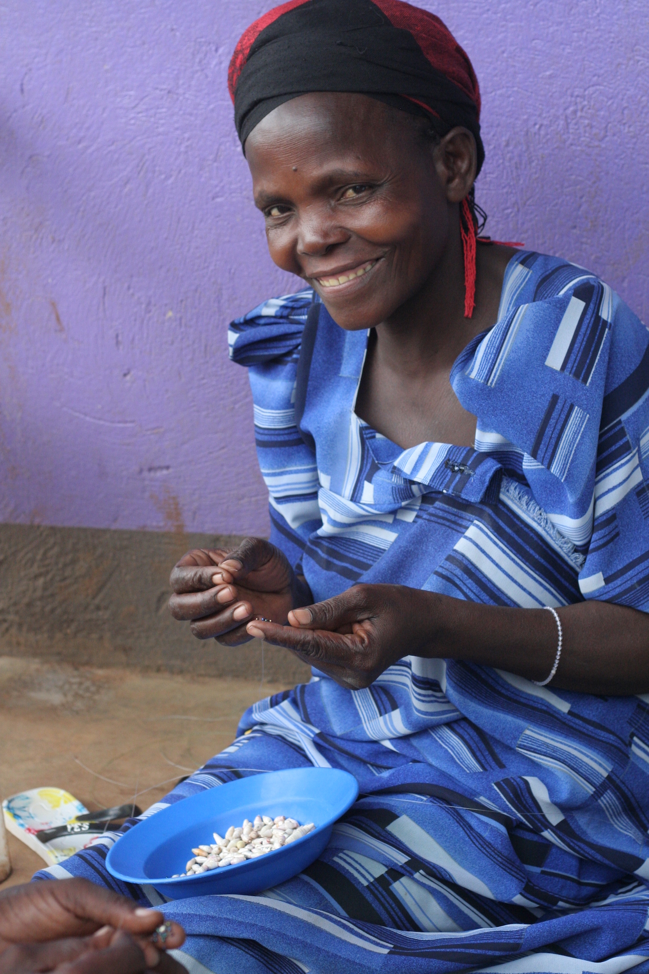 Woman smiling at the camera while stringing beads