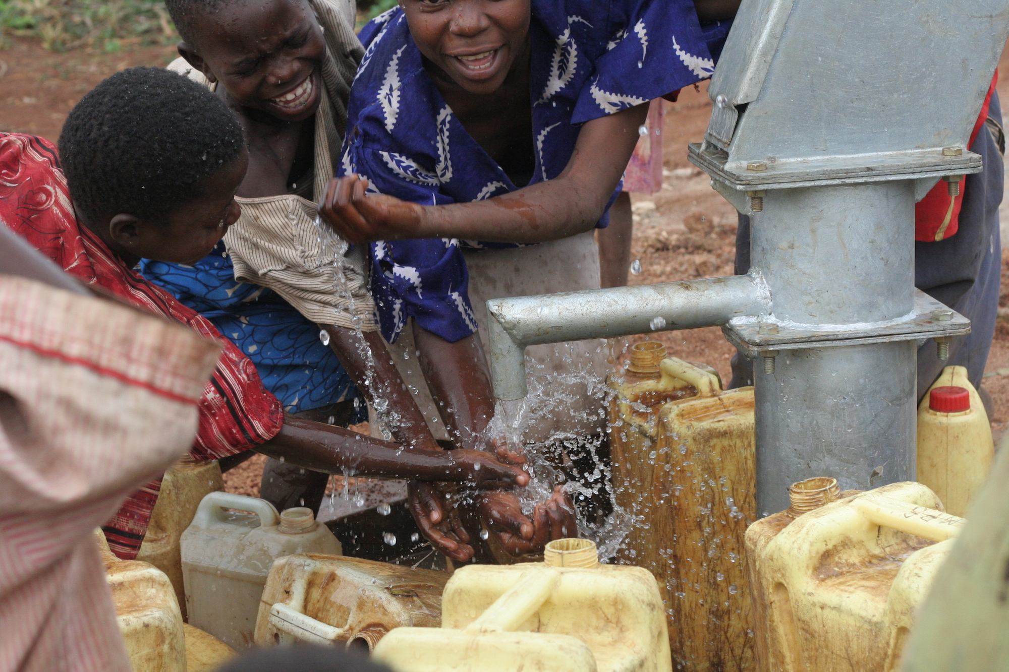 Smiling children at a water pump