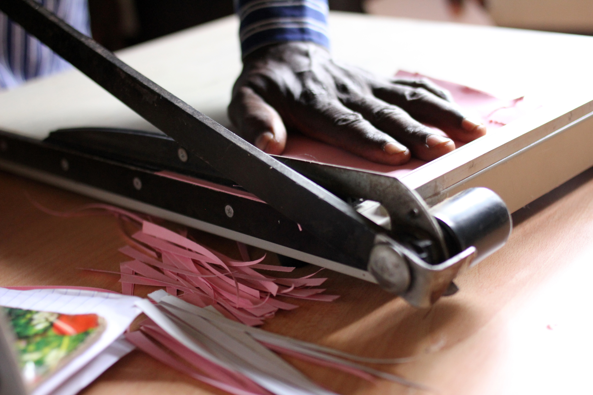 Man cutting strips of colored paper with a paper cutter