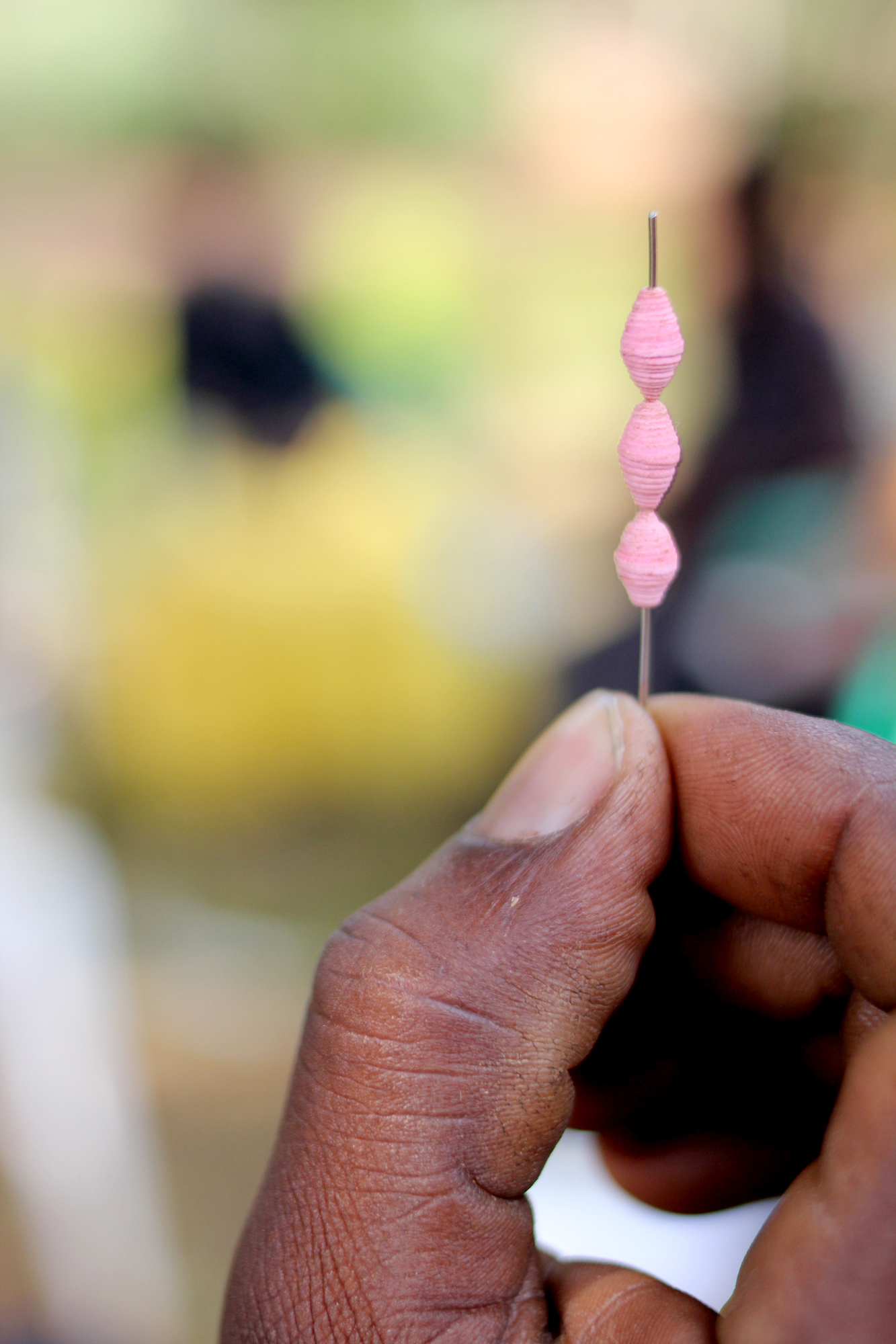 Three pink beads strung onto a needle