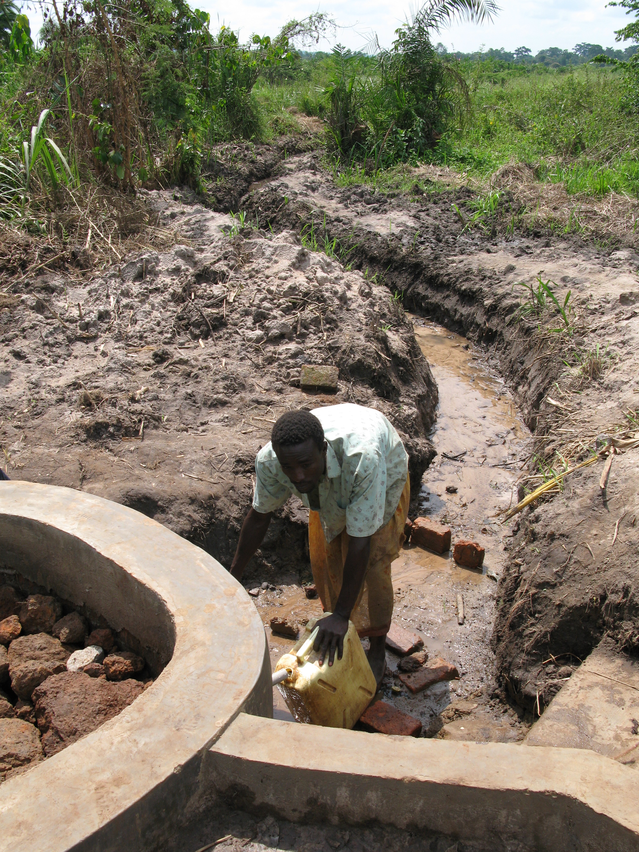 Man filling up a Jerry Can at a well.