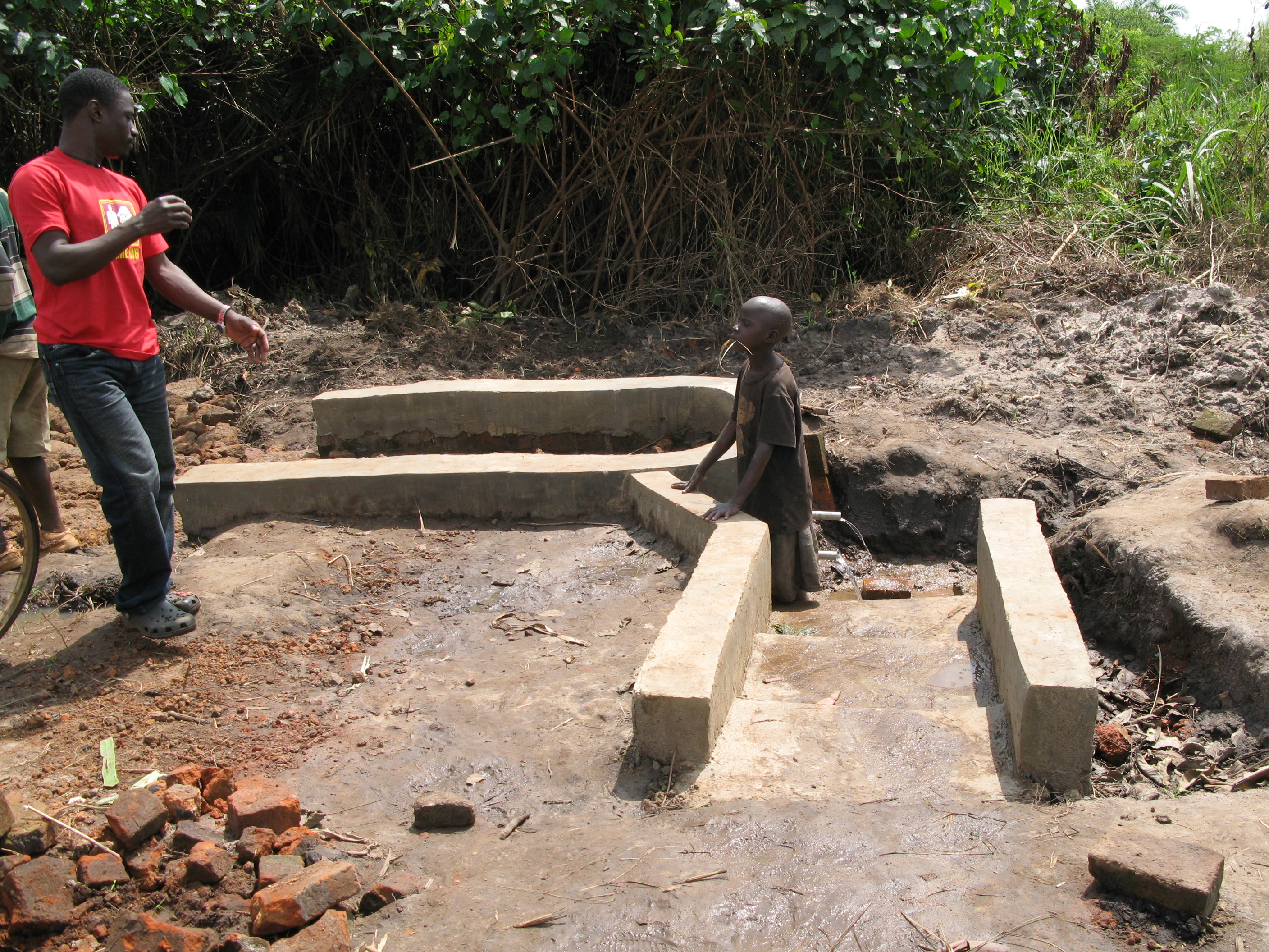 A man and a boy standing at a well.
