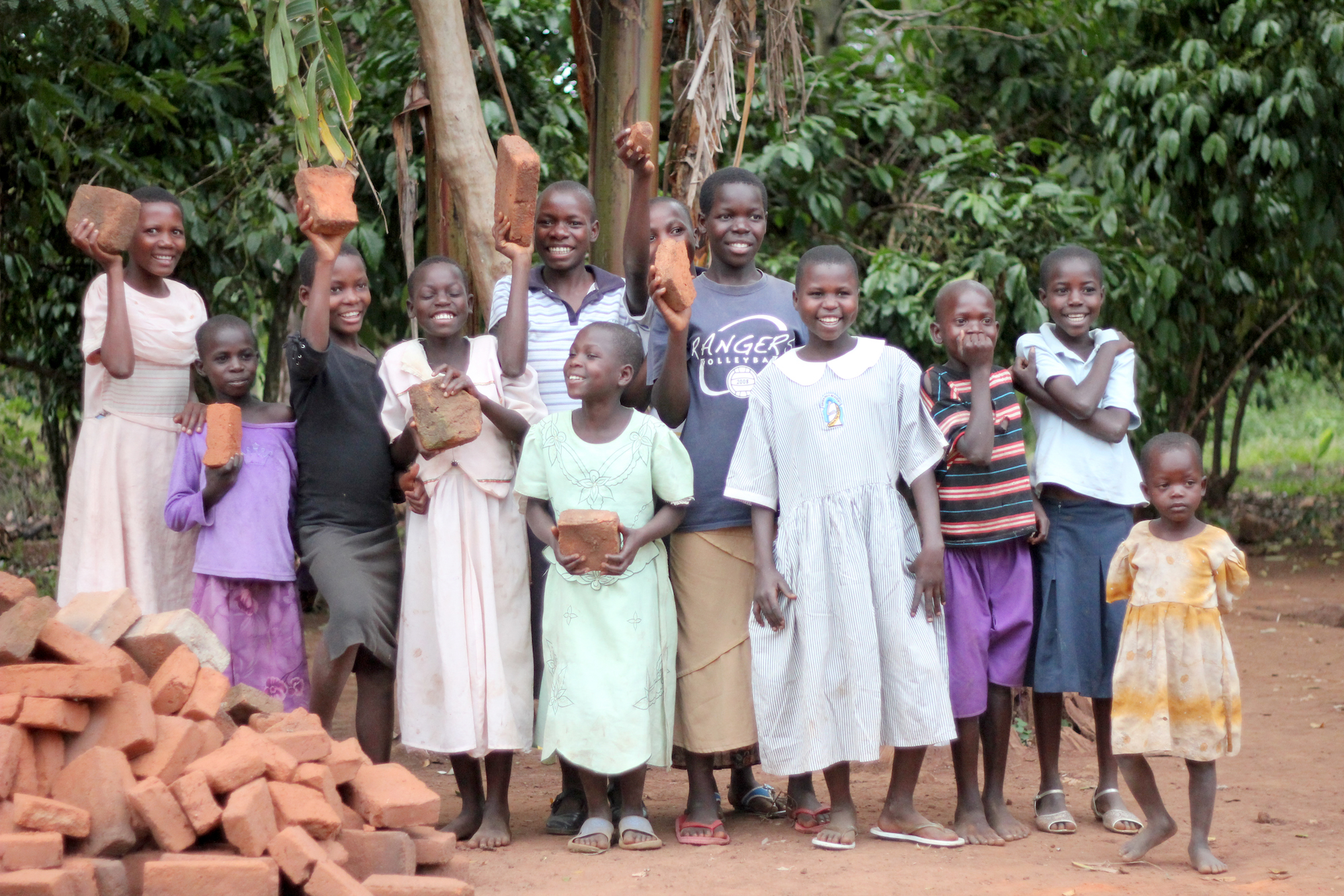 Group shot of smiling young people holding up bricks