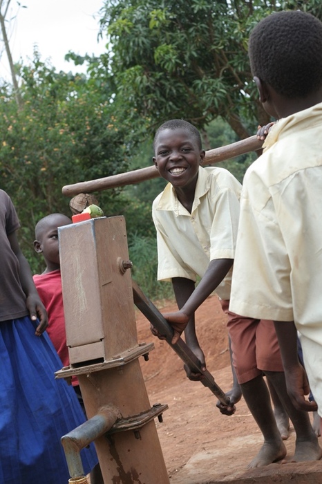 Smiling young boy at a water pump