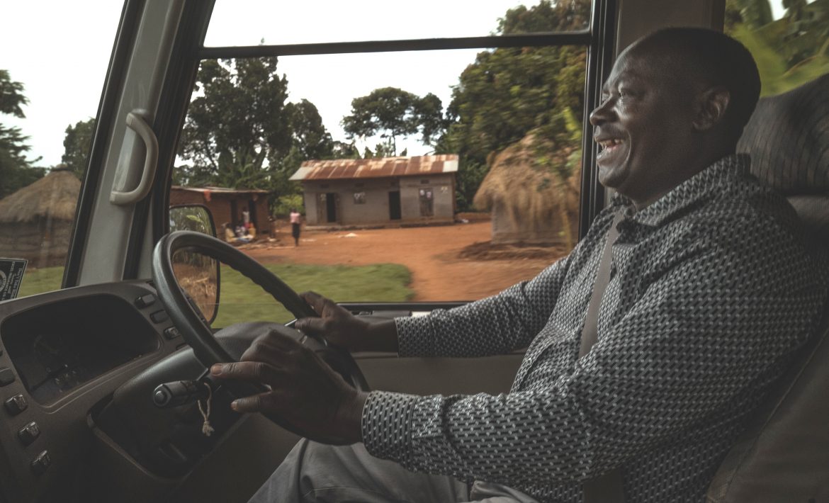 A man happily driving a bus in Uganda