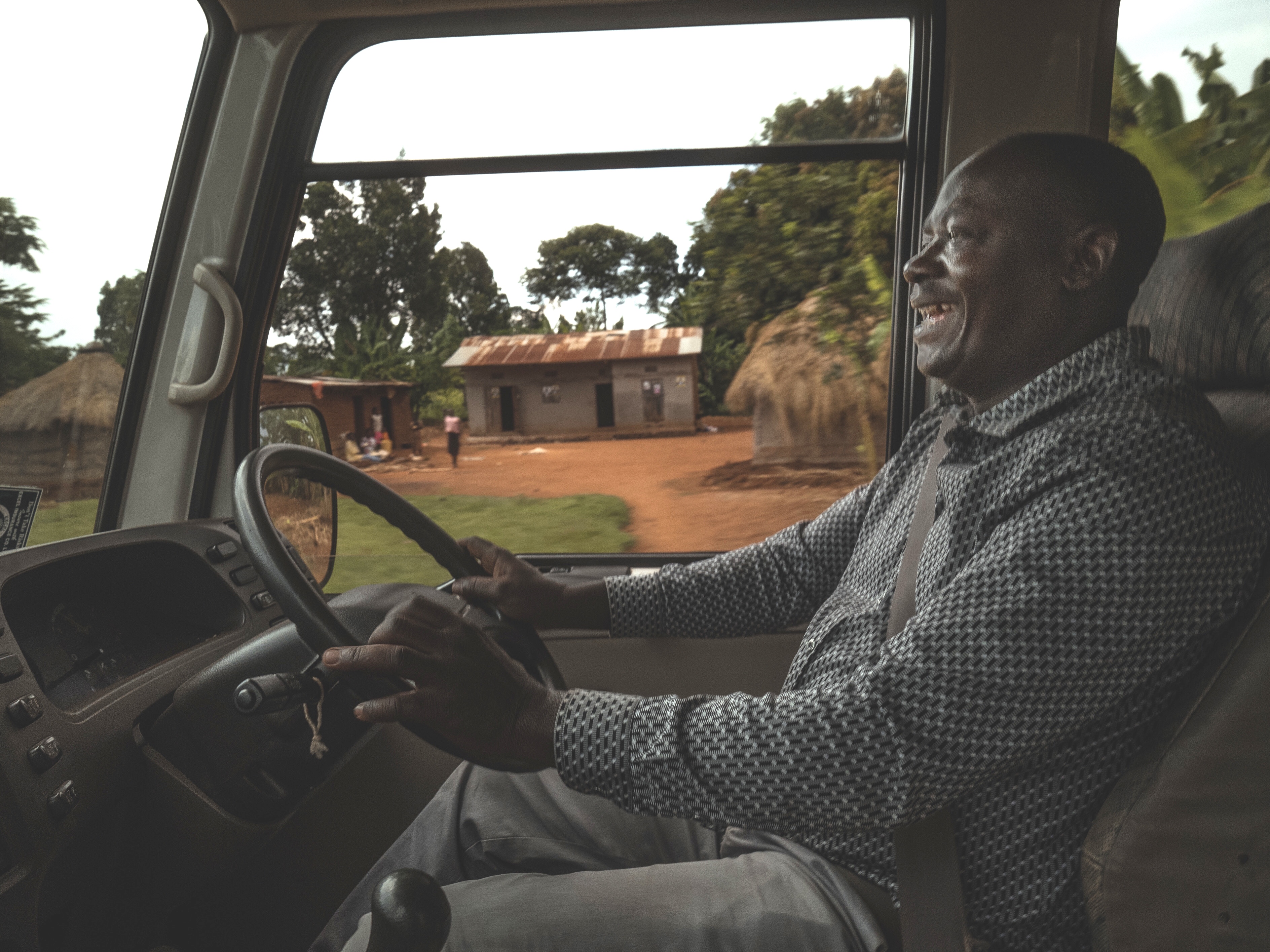 A man happily driving a bus in Uganda