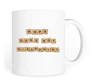 White mug with the words, "Hope does not disappoint" written on it in scrabble pieces