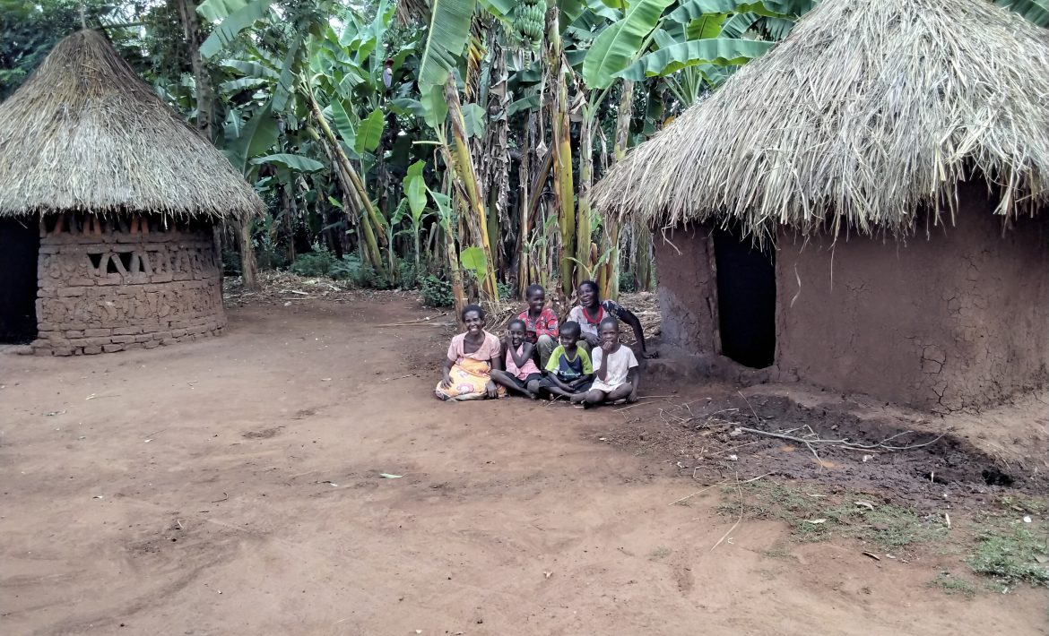 A woman and her family by their home in Uganda
