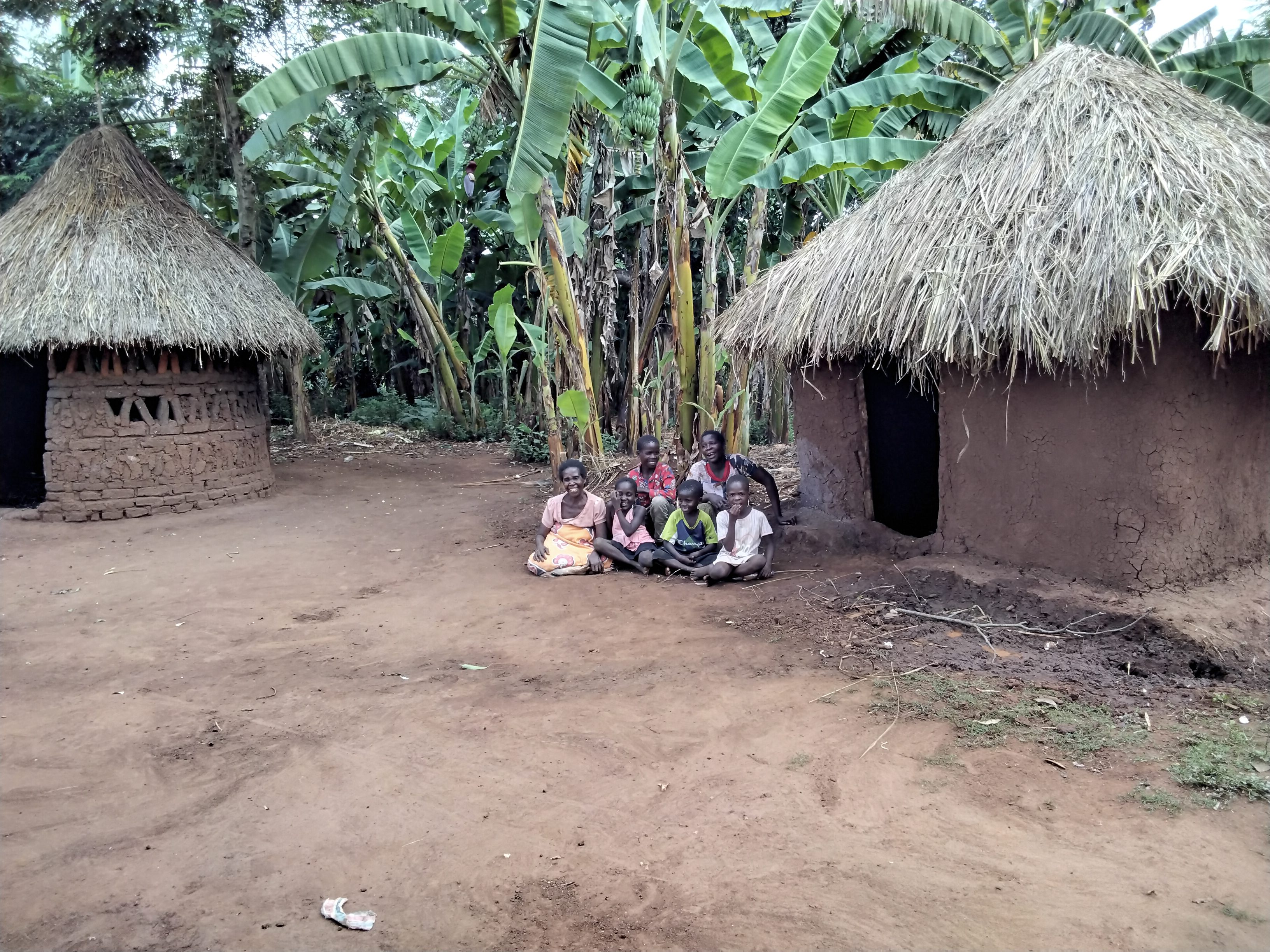 A woman and her family by their home in Uganda